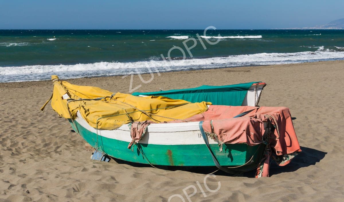 Colourful wooden fishing boat pulled up on a sandy beach