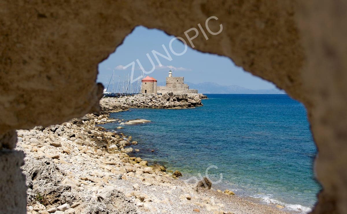 Sea view through a rock arch to a harbour fort