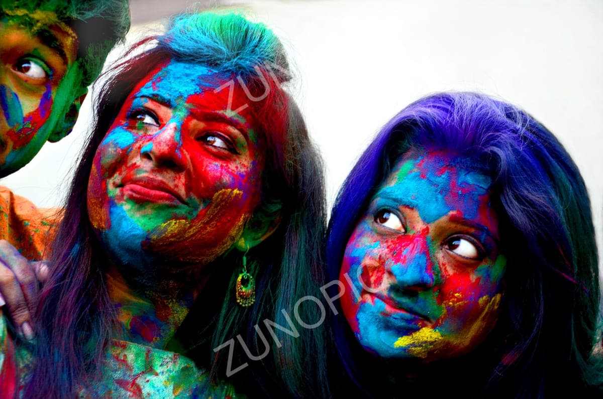 Friends with faces covered in Holi colours