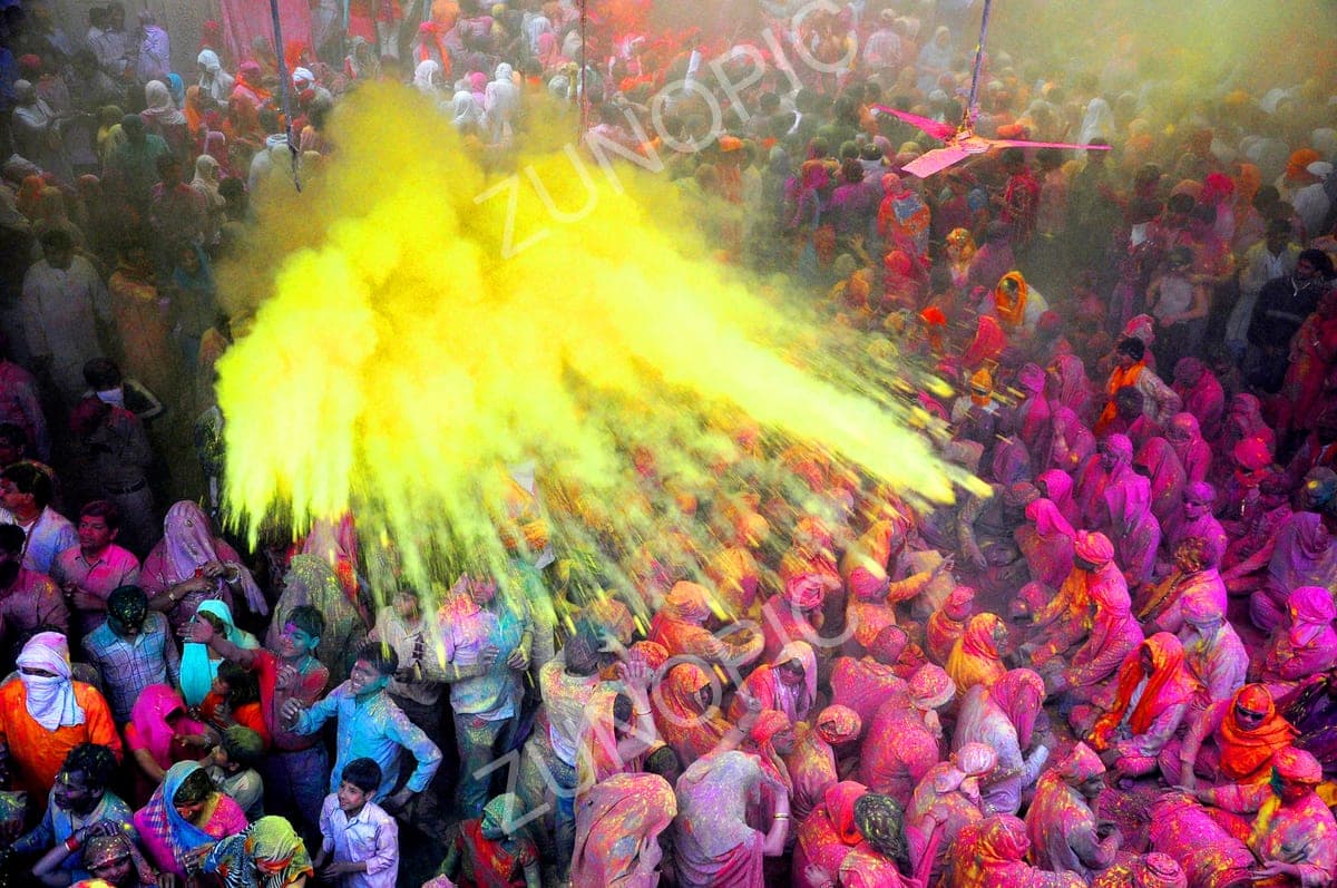 Clouds of coloured powder over a Holi crowd, aerial view