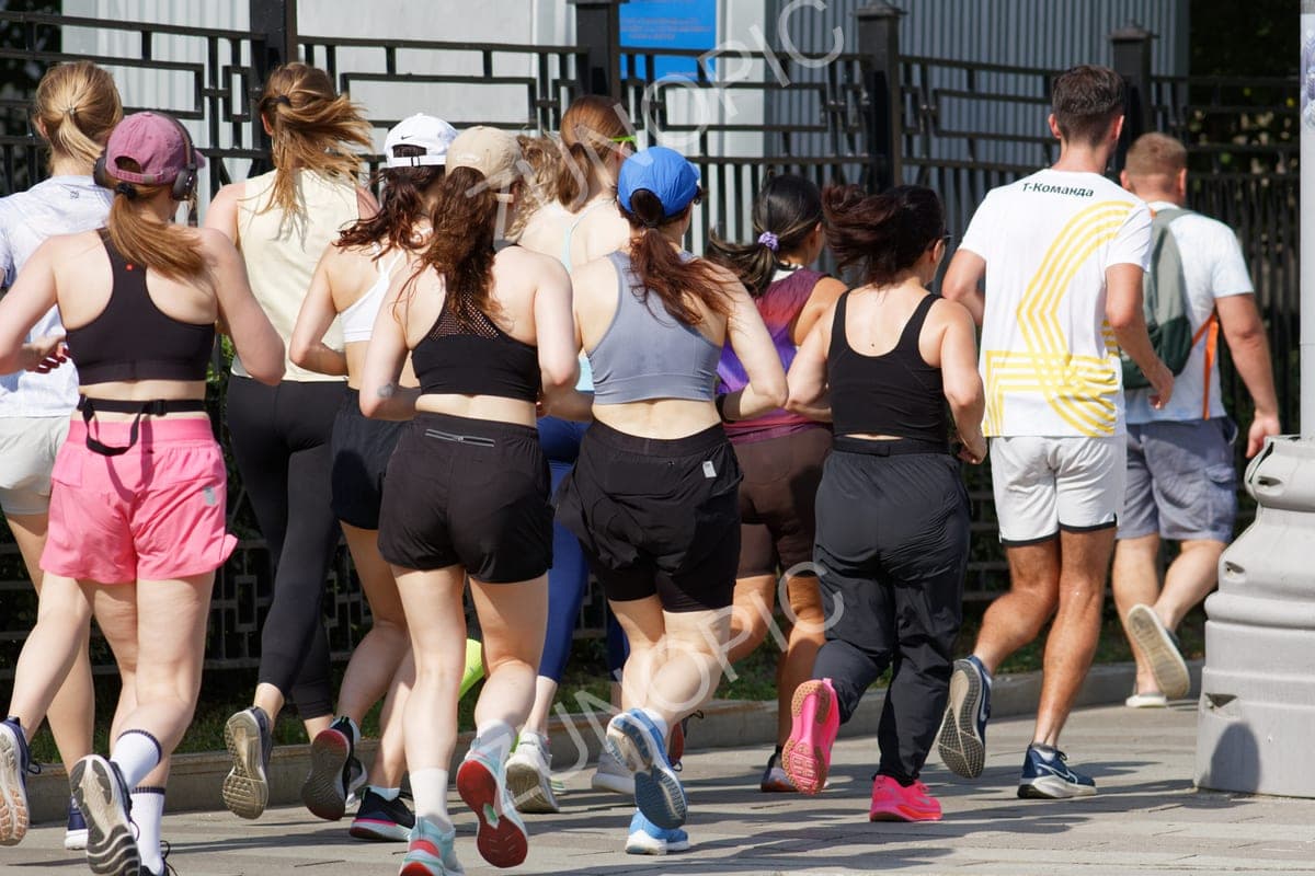 Group of runners jogging together in a city, rear view