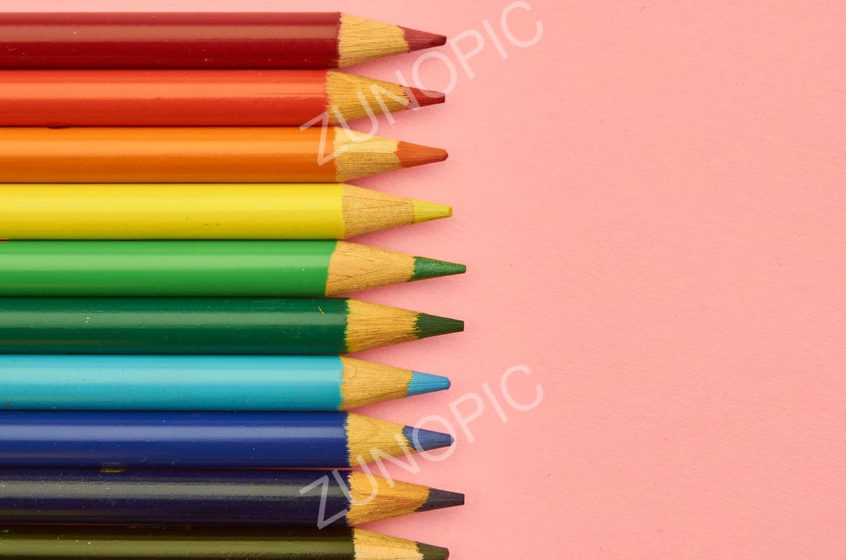 Coloured pencils lined up on a pink background