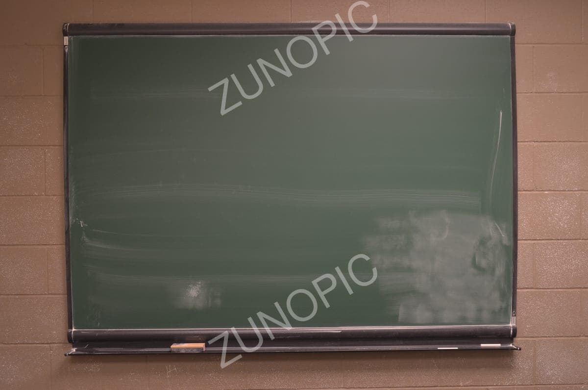 Blank green chalkboard on a brick wall