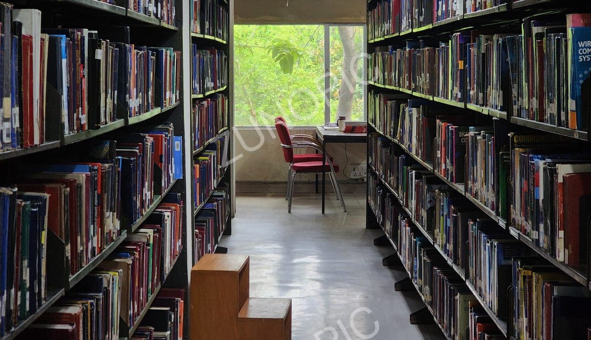 Library aisle between bookshelves with a reading chair